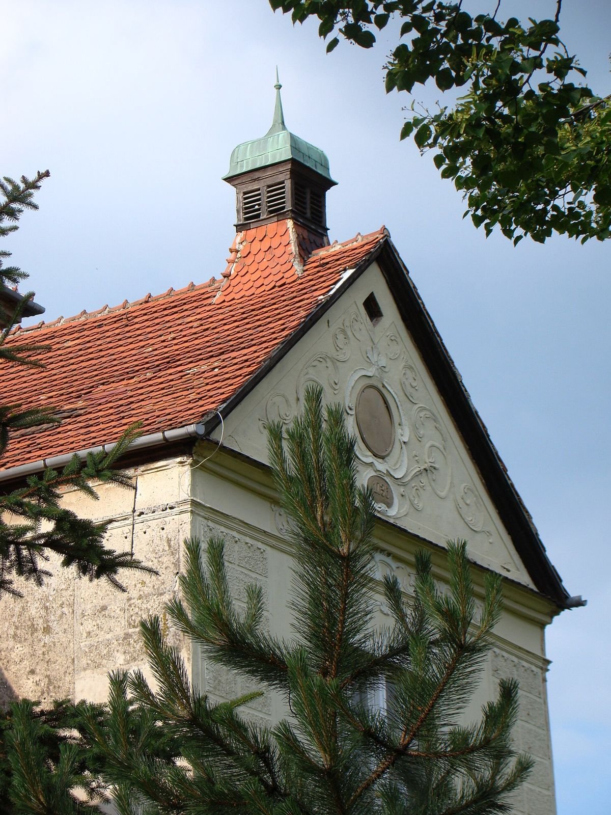 Szczyt ryzalitu pałacu w Jastrowcu z okrągłym otworem i sygnaturką na dachu.