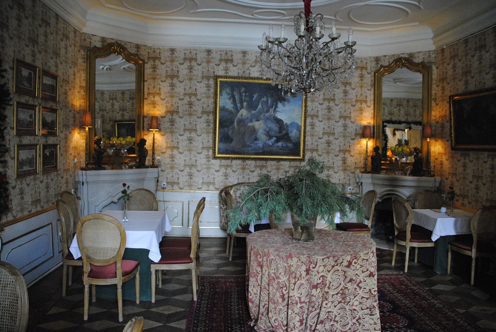 Wnętrze z tapetowanymi ścianami, lustrami, żyrandolem i nakrytymi stolikami (opis pliku: restauracja).