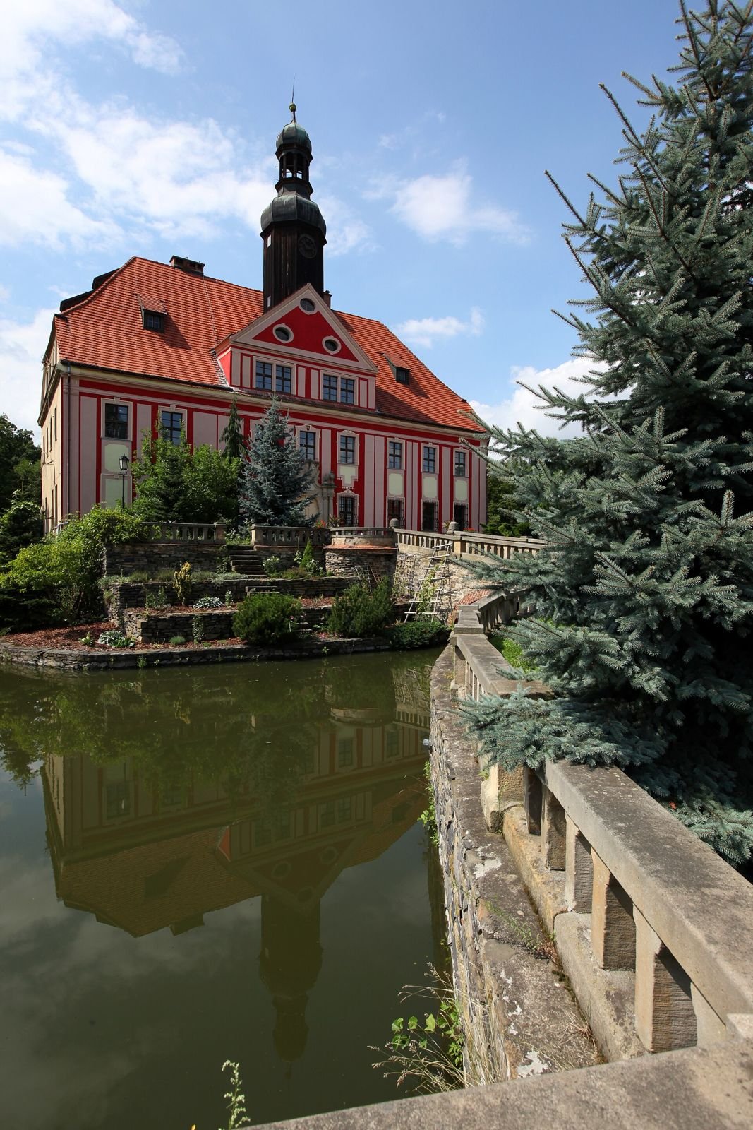 Pałac odbity w ciemnej wodzie, z kamienną balustradą na pierwszym planie.