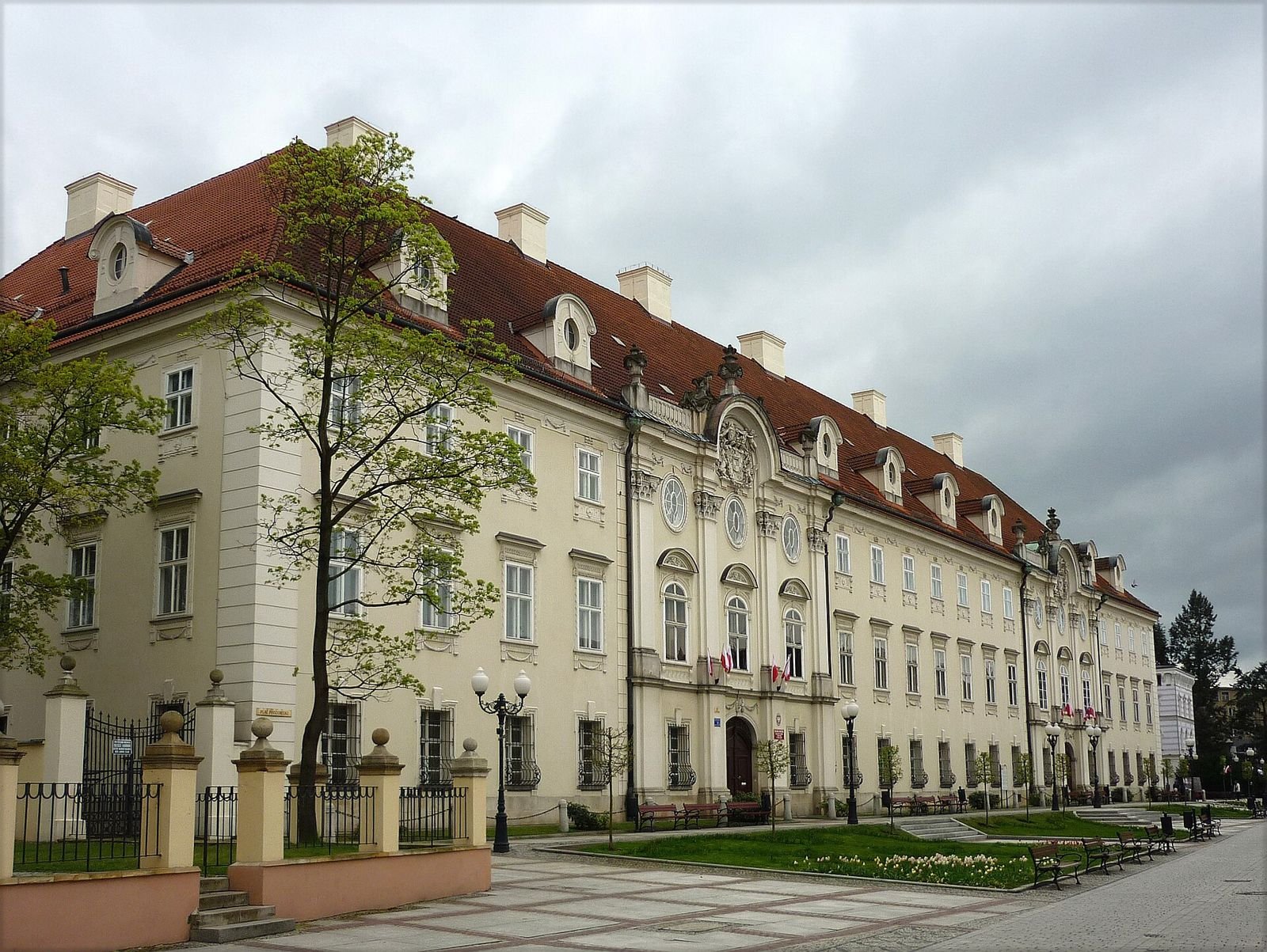 Długa fasada pałacu z bogato zdobionym portalem i ryzalitem środkowym, widziana z placu przed budynkiem.