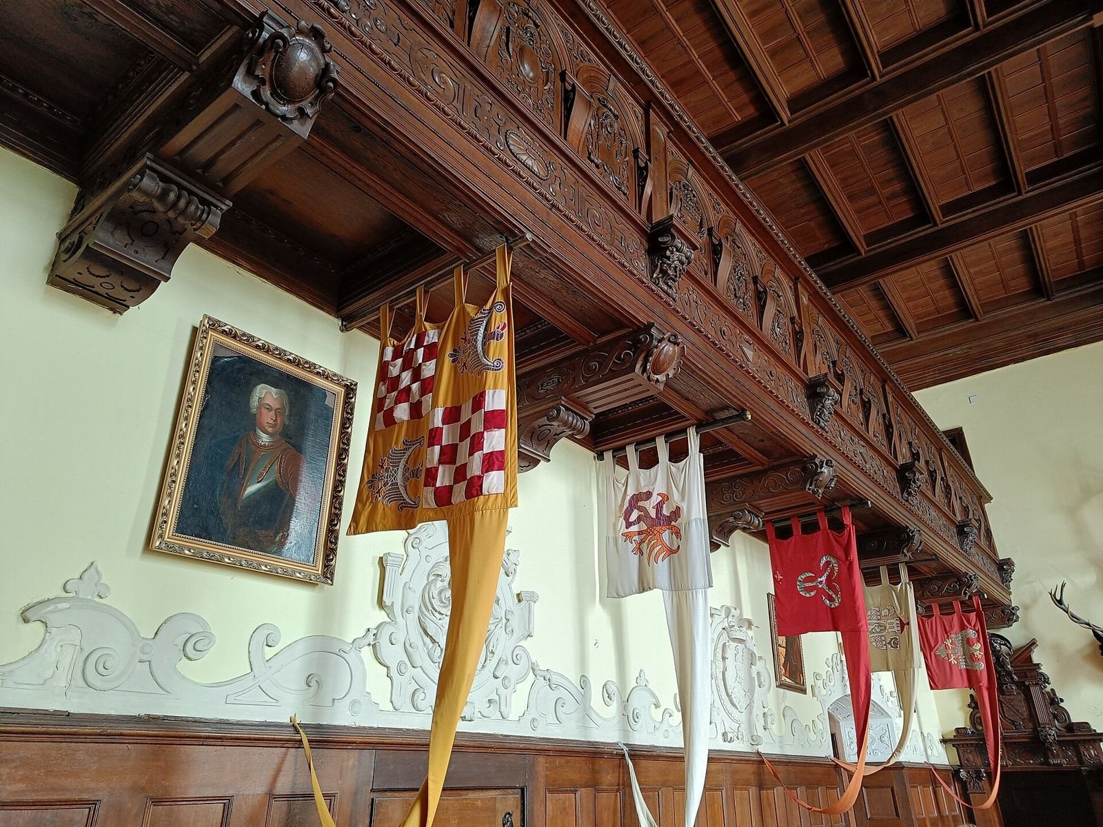 Sala w Zamku Czocha z drewnianym stropem, chorągwiami i portretem na ścianie