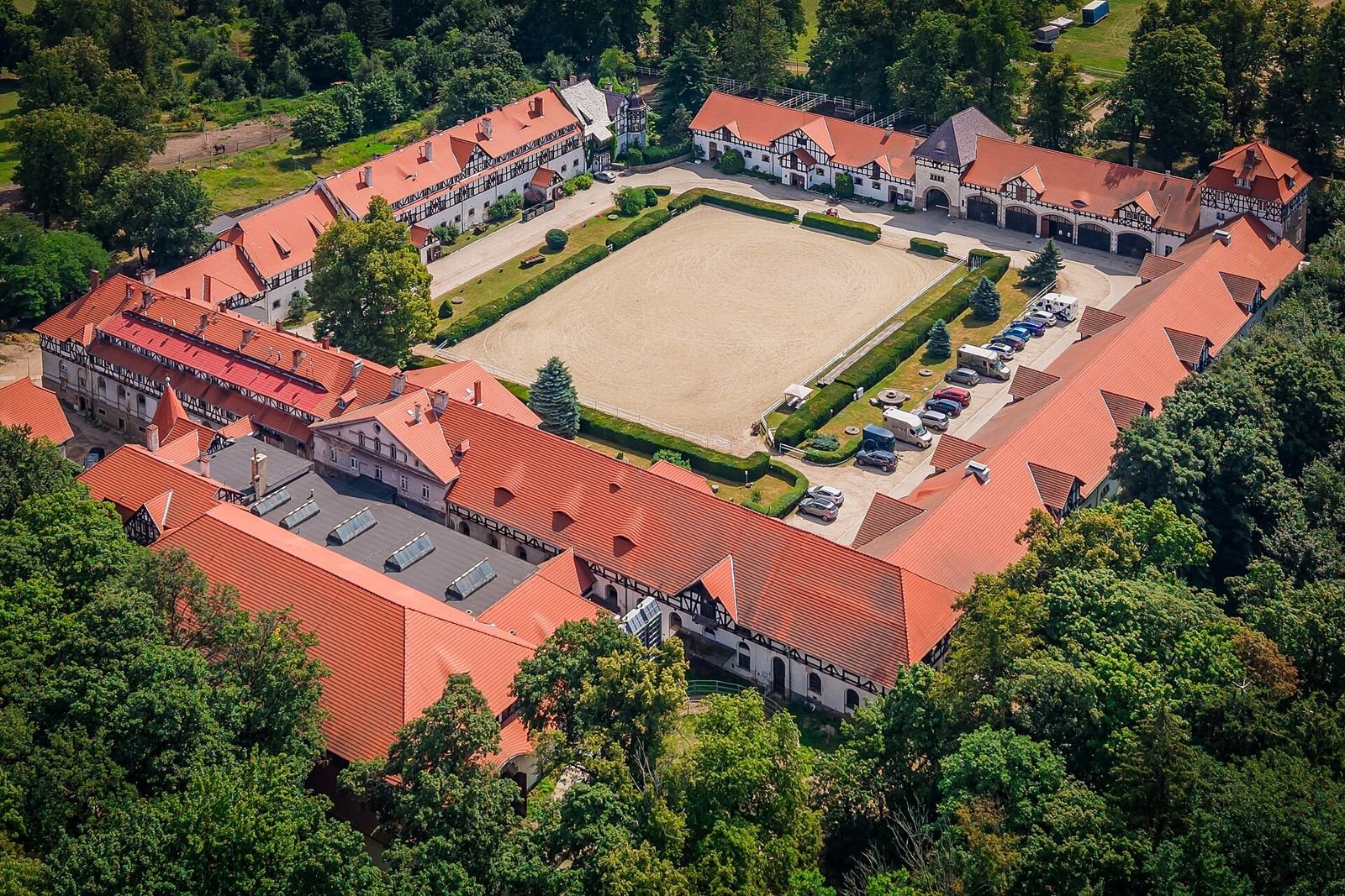 Stajnie Zamku Książ z lotu ptaka: zabudowania z czerwonymi dachami wokół prostokątnego placu.