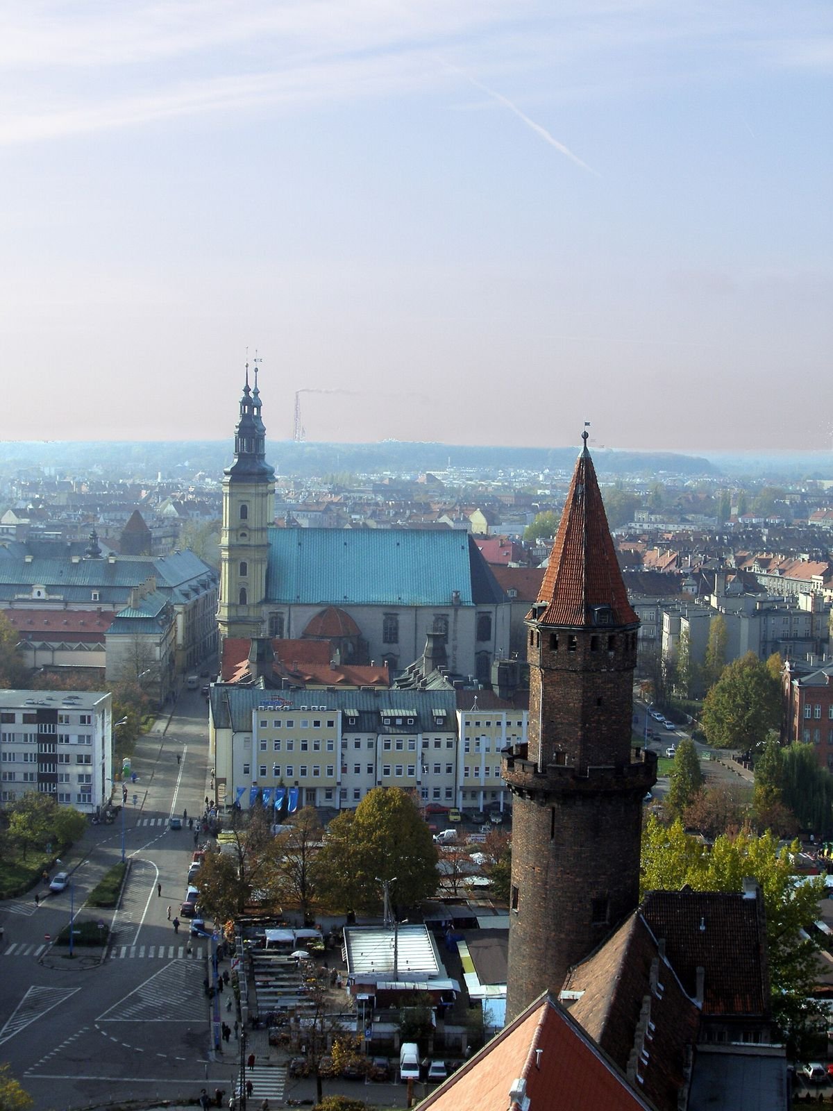 Widok z wieży na miasto: z lewej wieża kościoła, z prawej ceglana wieża zamkowa.