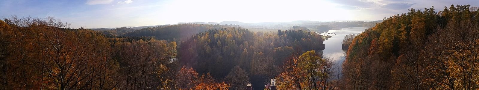 Panorama z wieży: zalesione, jesienne wzgórza i rzeka w dolinie.