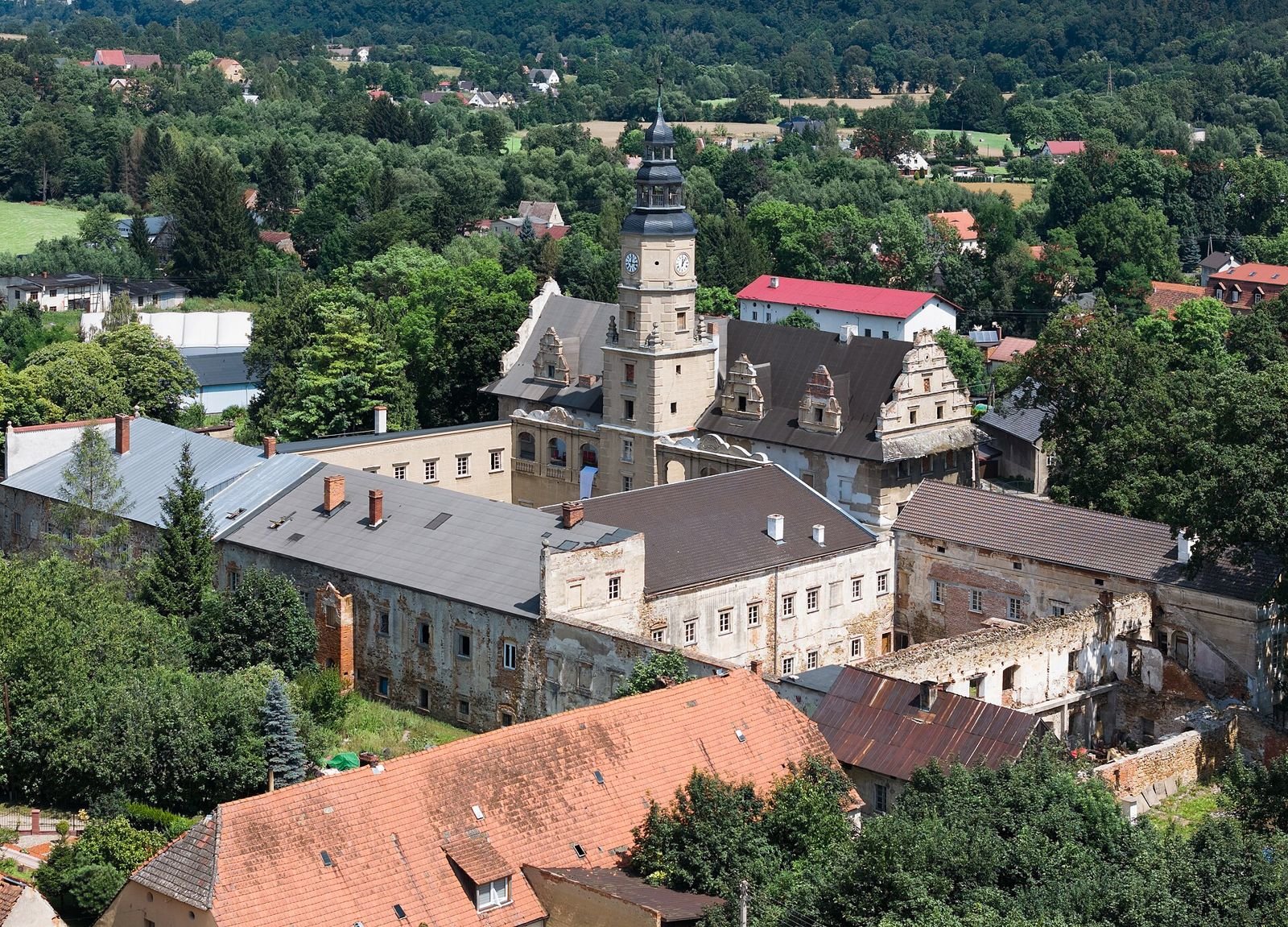Zespół zamkowy w Gorzanowie widziany z góry: dachy skrzydeł i wieża zegarowa wśród zieleni wsi.